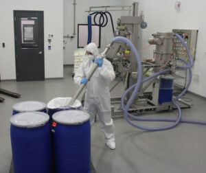 Operator transfers ingredients from commercial containers with a wand and vacuum conveyor